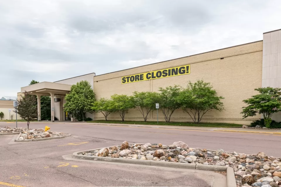 Large store in mall with yellow and black STORE CLOSING sign on front.